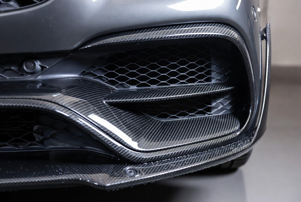 Bližnji posnetek karbonskega odbijača Mercedes AMG z dovodi zraka in parkirnimi senzorji